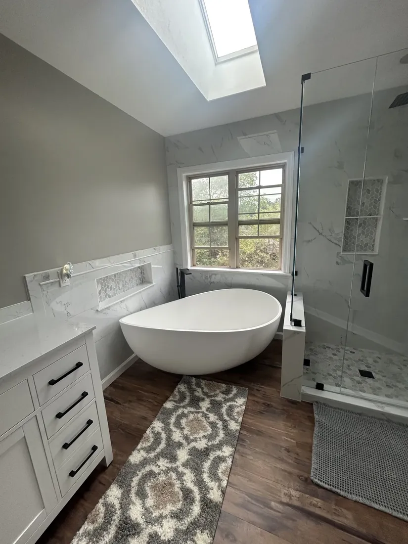 Freestanding soaking tub next to a marble-tiled walk-in shower