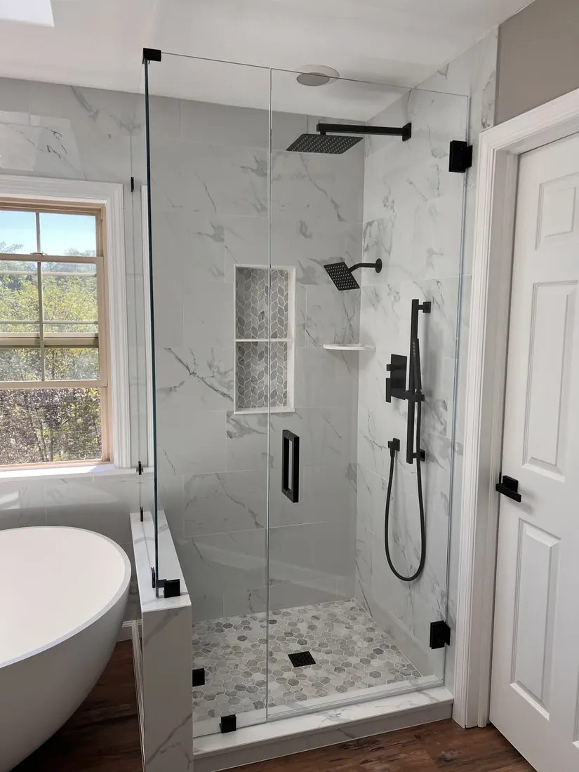 Marble walk-in shower with black fixtures and a tile niche